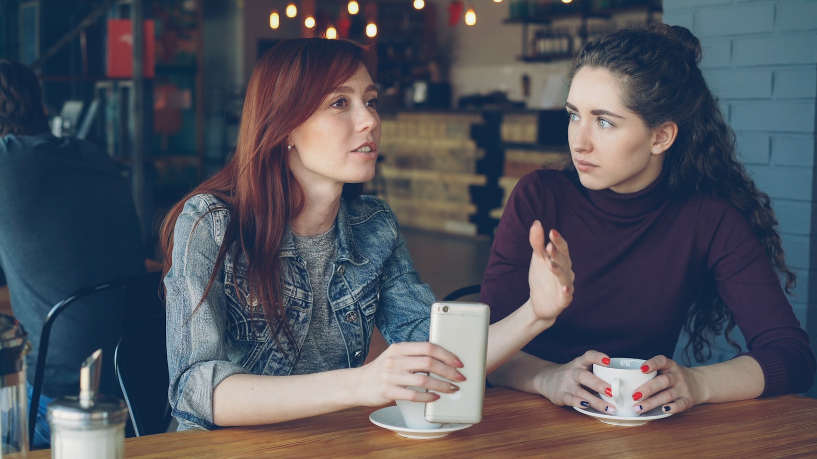 Duas pessoas em conversa próxima e genuína em uma mesa de café