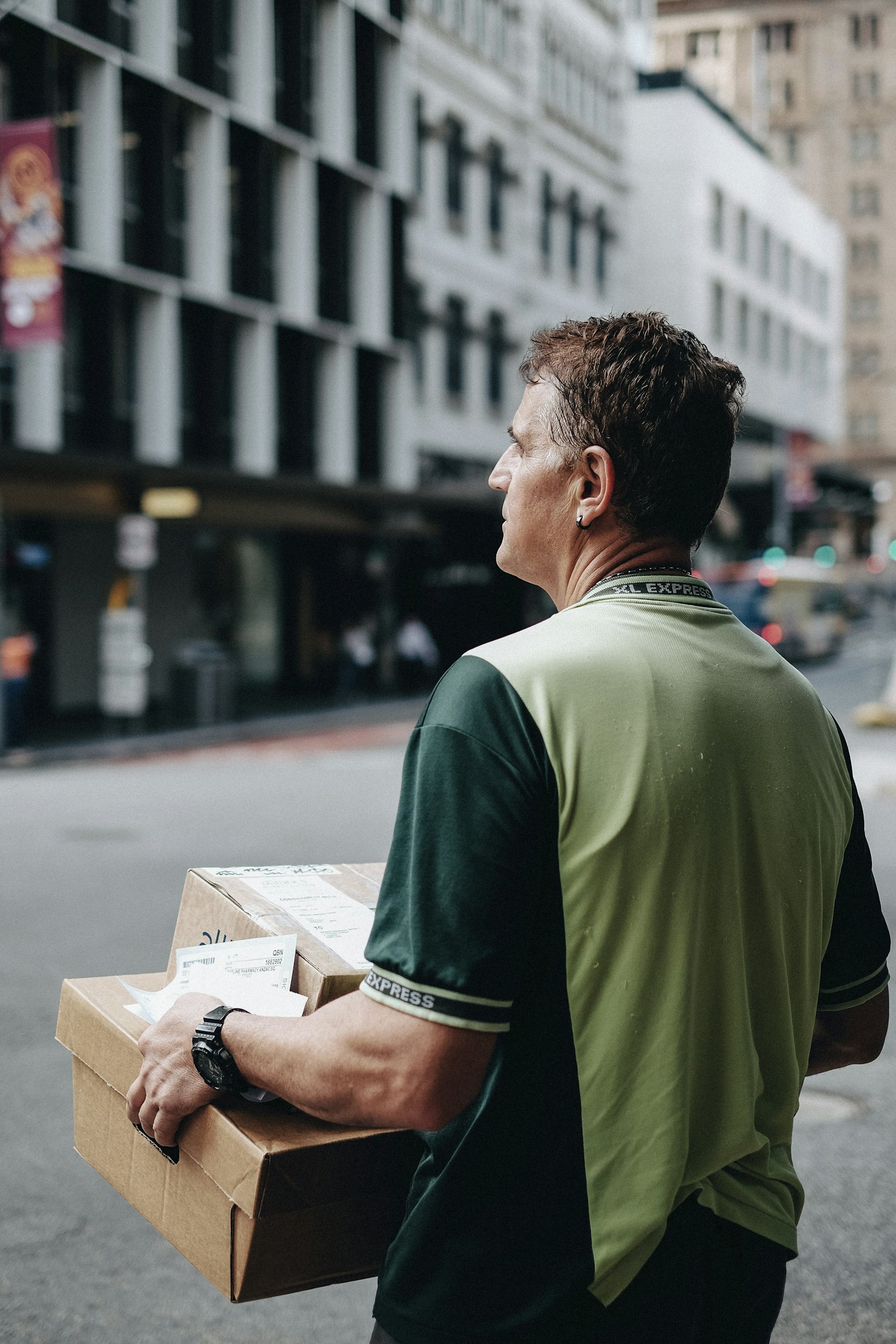 Entregador carregando uma caixa pela rua, levando o pedido até o destino